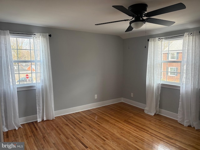 spare room with a healthy amount of sunlight, baseboards, and wood finished floors