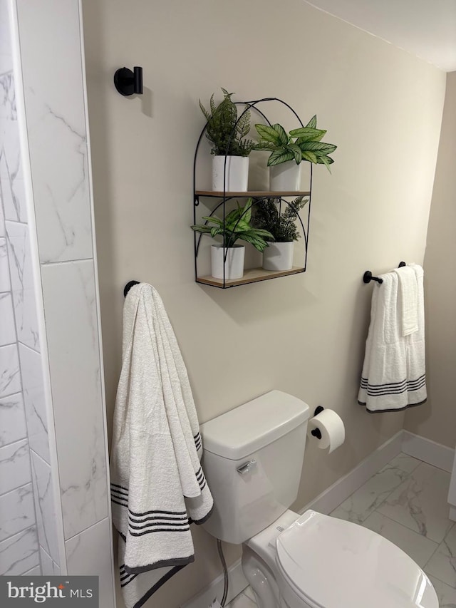 bathroom with marble finish floor, toilet, and baseboards