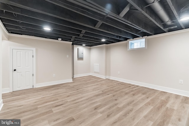 below grade area with light wood-type flooring, electric panel, and baseboards