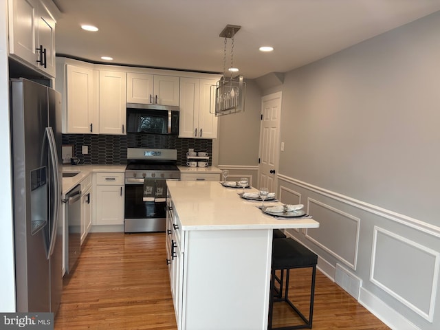 kitchen with decorative backsplash, a kitchen island, a breakfast bar area, stainless steel appliances, and light countertops