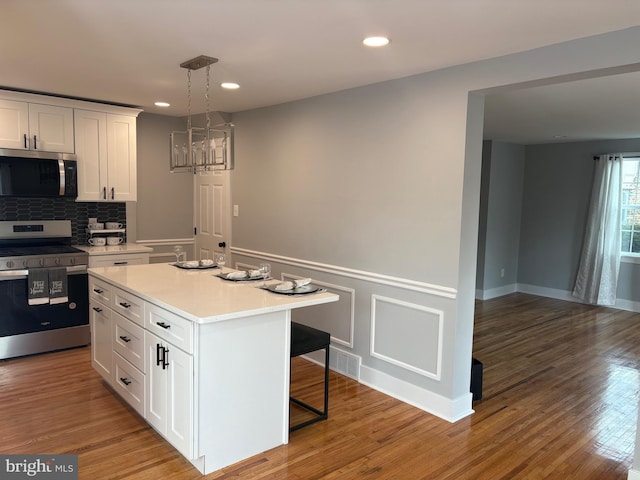 kitchen with a breakfast bar area, appliances with stainless steel finishes, light countertops, and wood finished floors