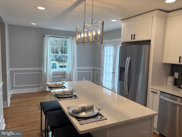 kitchen with appliances with stainless steel finishes, wainscoting, and white cabinets