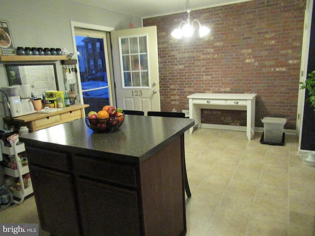 kitchen featuring dark countertops, a notable chandelier, and brick wall