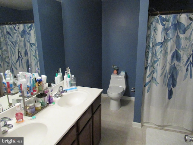 full bathroom with toilet, double vanity, a sink, and tile patterned floors