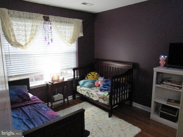 bedroom featuring wood finished floors, visible vents, and baseboards