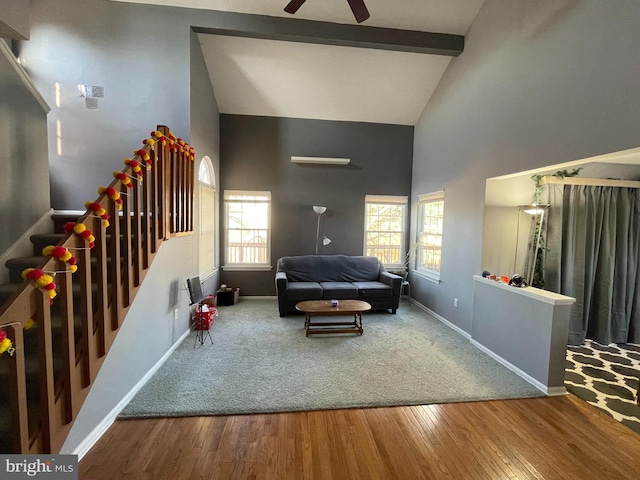 living room featuring high vaulted ceiling, wood finished floors, baseboards, stairs, and beam ceiling