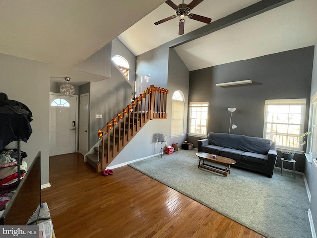 living area with ceiling fan, high vaulted ceiling, wood finished floors, baseboards, and stairway