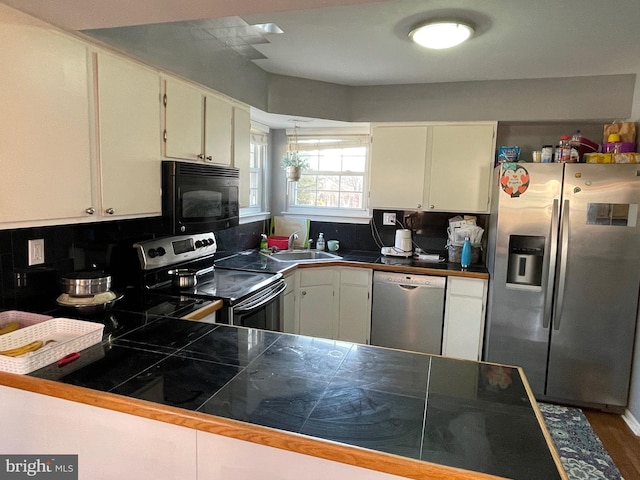 kitchen with a sink, white cabinets, appliances with stainless steel finishes, tasteful backsplash, and dark countertops