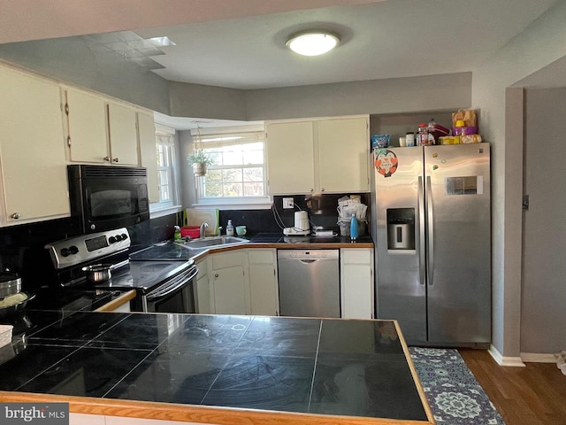 kitchen featuring dark wood-style floors, appliances with stainless steel finishes, a sink, and white cabinetry