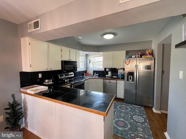 kitchen featuring stainless steel appliances, visible vents, white cabinets, a sink, and a peninsula