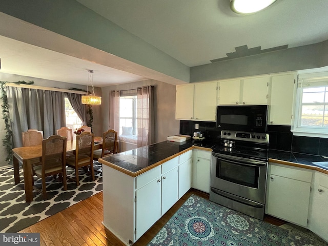 kitchen featuring black microwave, a peninsula, stainless steel range with electric cooktop, tasteful backsplash, and dark wood finished floors