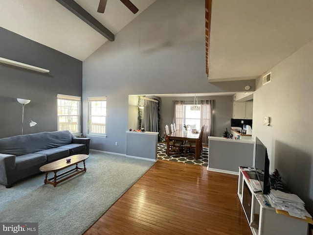 living area with a wealth of natural light, wood-type flooring, visible vents, and beamed ceiling