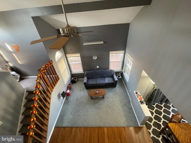 unfurnished living room with a high ceiling, wood finished floors, a ceiling fan, baseboards, and stairs