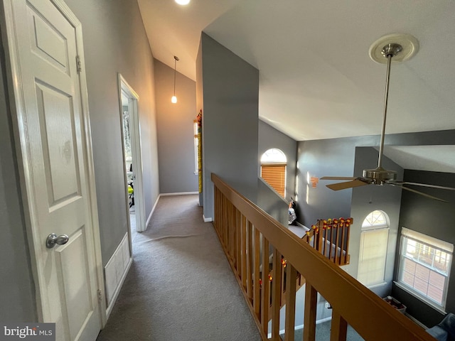 hallway featuring lofted ceiling, baseboards, carpet floors, and an upstairs landing