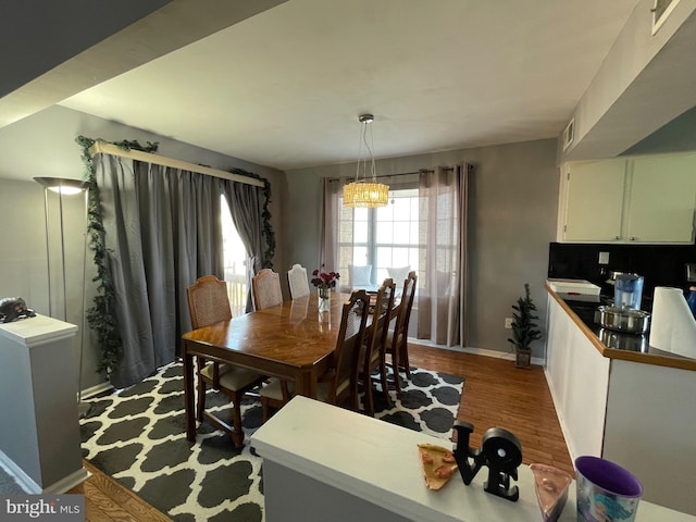 dining area with a notable chandelier, baseboards, and wood finished floors