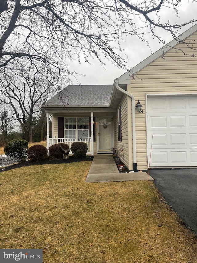 view of front of home with a garage, covered porch, a front lawn, and a shingled roof