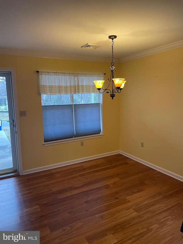 unfurnished dining area featuring wood finished floors, baseboards, visible vents, crown molding, and a chandelier