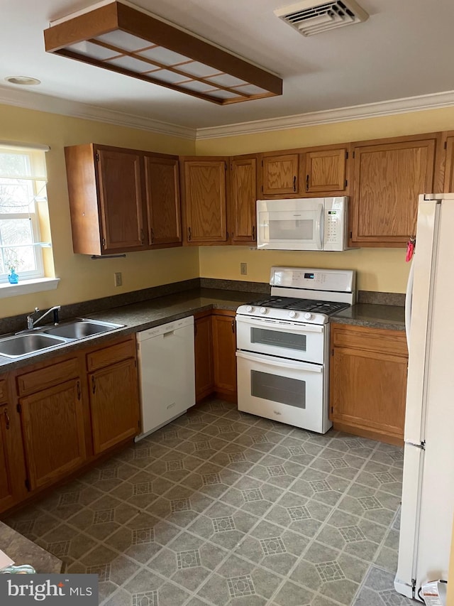 kitchen featuring dark countertops, visible vents, ornamental molding, white appliances, and a sink