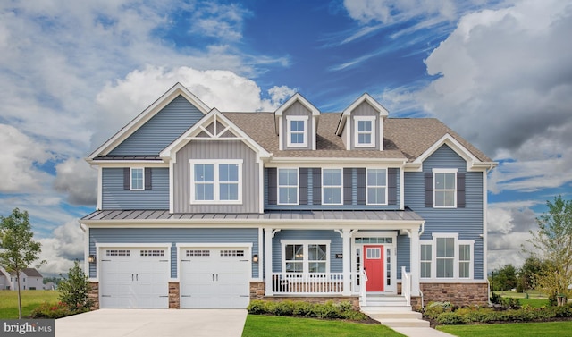 view of front of property with an attached garage, covered porch, driveway, stone siding, and a standing seam roof