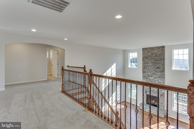 hallway with arched walkways, recessed lighting, an upstairs landing, baseboards, and visible vents