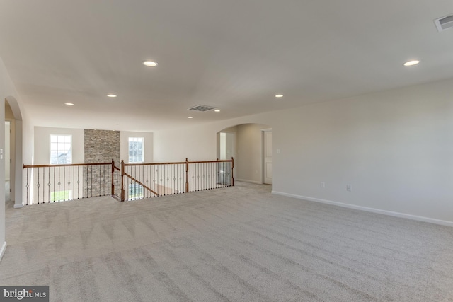 unfurnished room featuring arched walkways, light colored carpet, and recessed lighting