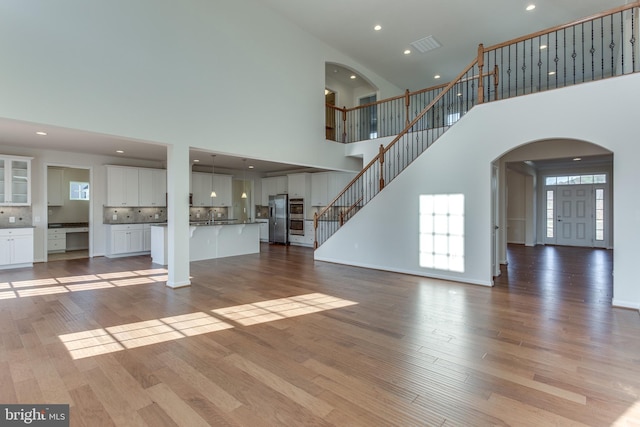 unfurnished living room featuring light wood finished floors, stairway, visible vents, and recessed lighting