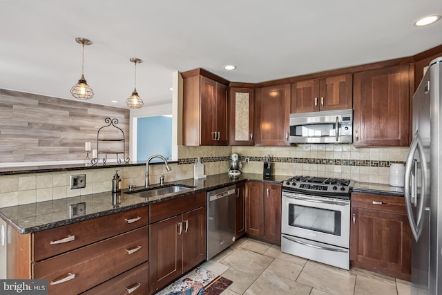 kitchen featuring pendant lighting, a sink, tasteful backsplash, stainless steel appliances, and dark stone counters