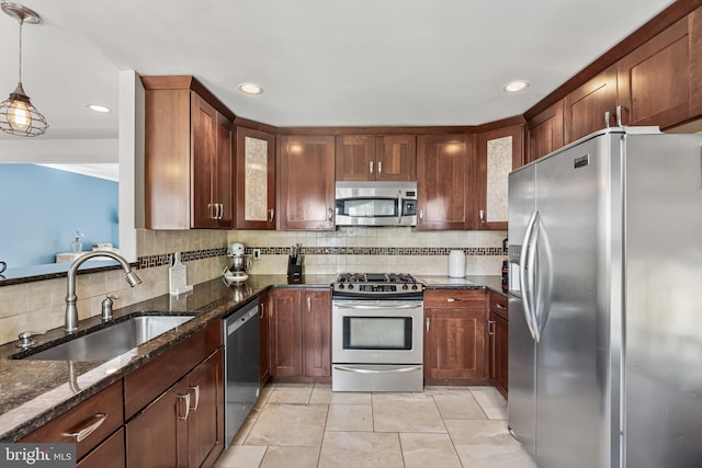 kitchen with dark stone countertops, a sink, decorative backsplash, glass insert cabinets, and appliances with stainless steel finishes