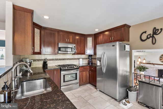 kitchen with a sink, dark stone countertops, tasteful backsplash, appliances with stainless steel finishes, and light tile patterned floors