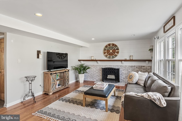 living room with recessed lighting, baseboards, a brick fireplace, and wood finished floors