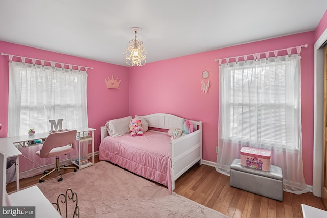 bedroom featuring multiple windows, baseboards, wood-type flooring, and a chandelier