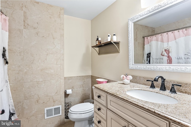 full bath with visible vents, toilet, vanity, a shower with curtain, and tile walls