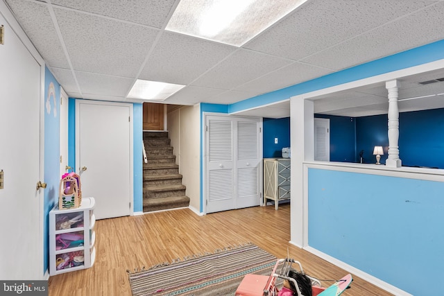 interior space featuring wood finished floors, visible vents, baseboards, a drop ceiling, and stairs