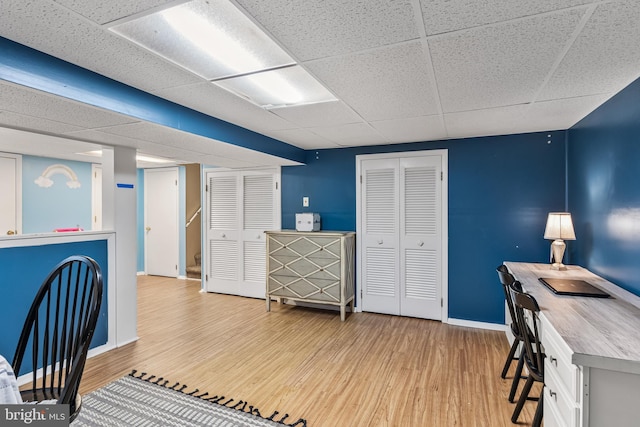 office area with a paneled ceiling, baseboards, and wood finished floors