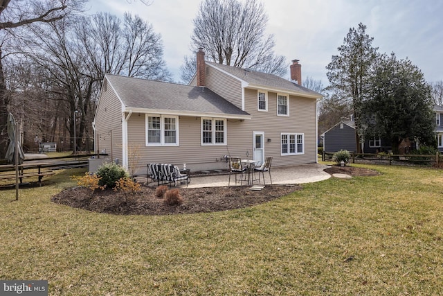 back of property with fence, a yard, a shingled roof, a chimney, and a patio area