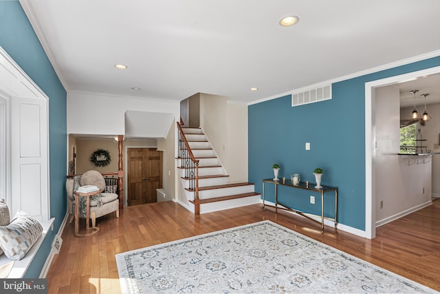 foyer entrance featuring visible vents, wood-type flooring, baseboards, and crown molding