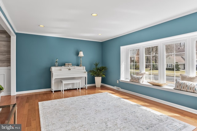 sitting room featuring visible vents, baseboards, wood finished floors, and crown molding