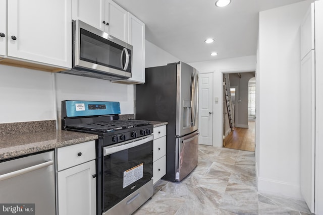 kitchen featuring dark stone counters, stainless steel appliances, white cabinetry, and recessed lighting