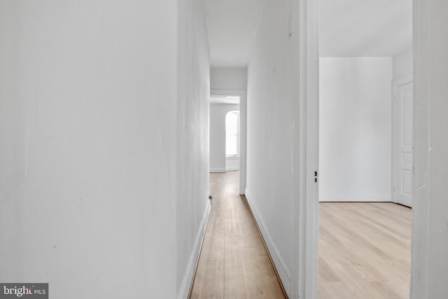 hall with baseboards and light wood finished floors