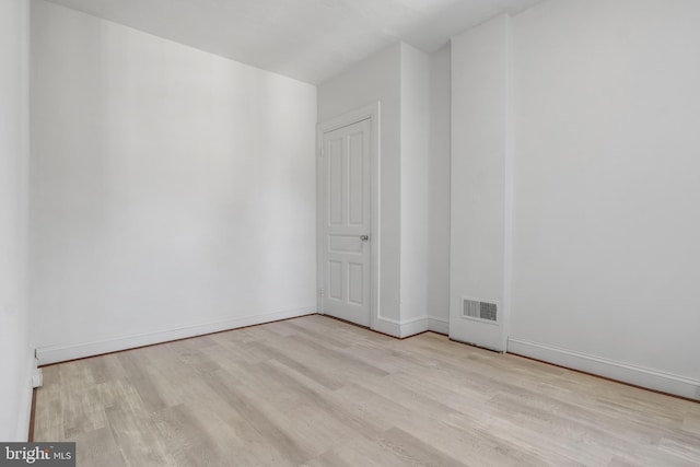 unfurnished room featuring wood finished floors, visible vents, and baseboards