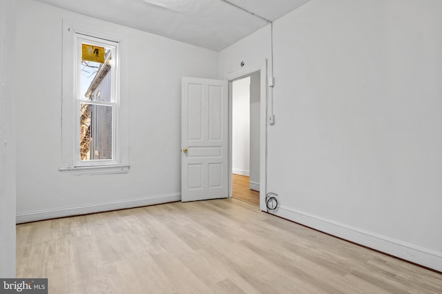 spare room featuring plenty of natural light, wood finished floors, and baseboards