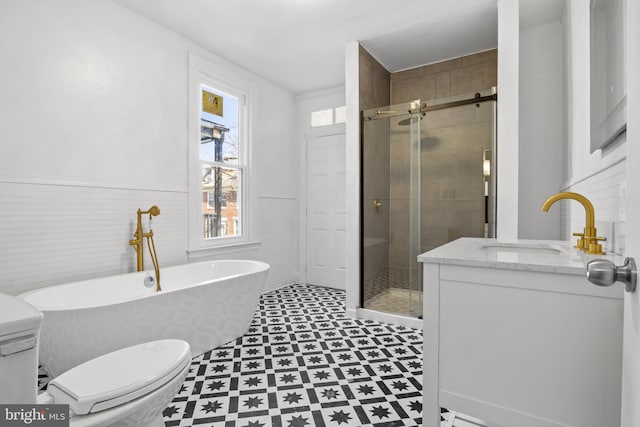 bathroom with wainscoting, tile patterned floors, a freestanding bath, a shower stall, and a sink