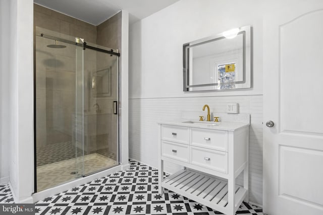 full bath featuring a stall shower, a wainscoted wall, tile walls, and vanity