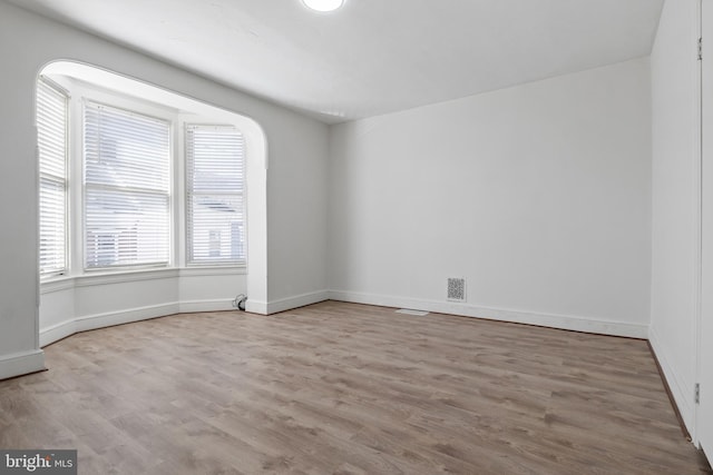 empty room featuring visible vents, baseboards, and wood finished floors