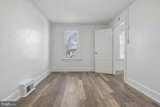 unfurnished room with baseboards, visible vents, and wood finished floors