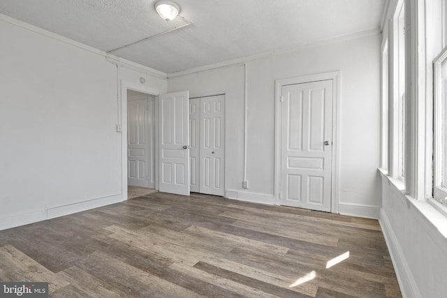 unfurnished bedroom with a textured ceiling, baseboards, and wood finished floors