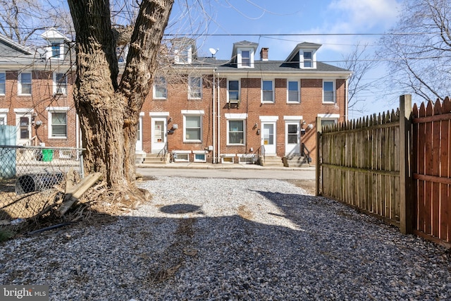 back of property with entry steps, brick siding, and fence