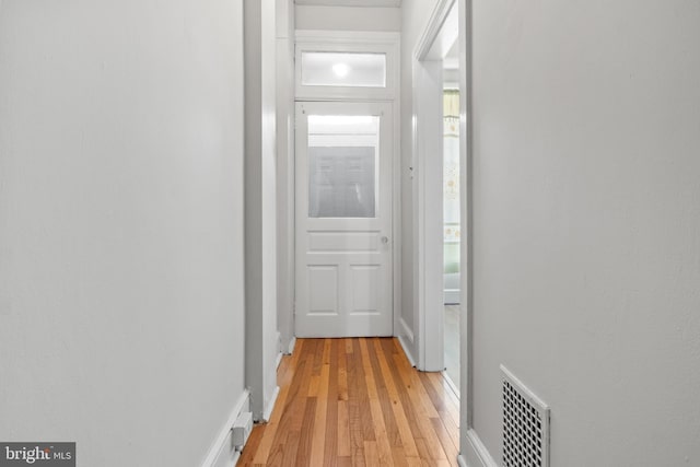 hall featuring light wood-type flooring, visible vents, and baseboards