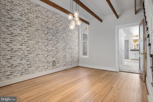 unfurnished room with brick wall, light wood-style flooring, baseboards, and beamed ceiling