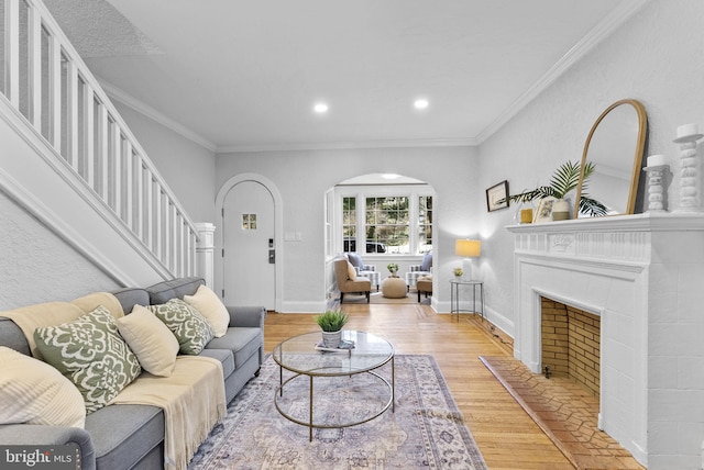 living area featuring arched walkways, crown molding, baseboards, and wood finished floors